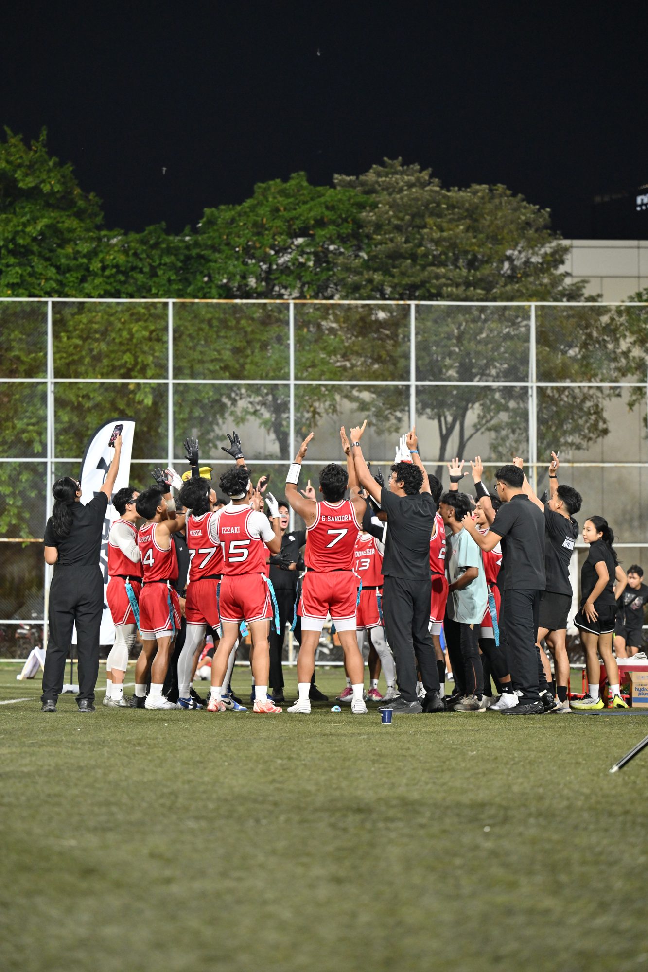 Tim Putra Indonesia bersama staf pelatih merayakan kemenangan di pinggir lapangan.